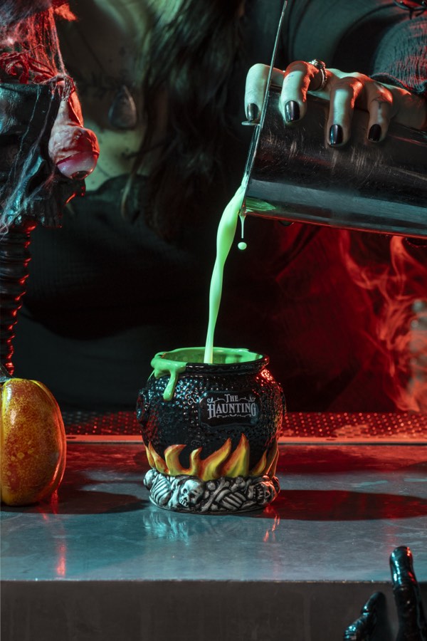 Green cocktail pouring into a Haunted cauldron mug